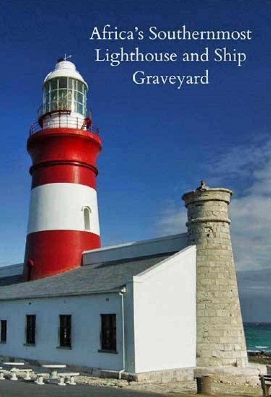 Africa's southernmost lighthouse with red and white stripes, a stone tower, and white building.